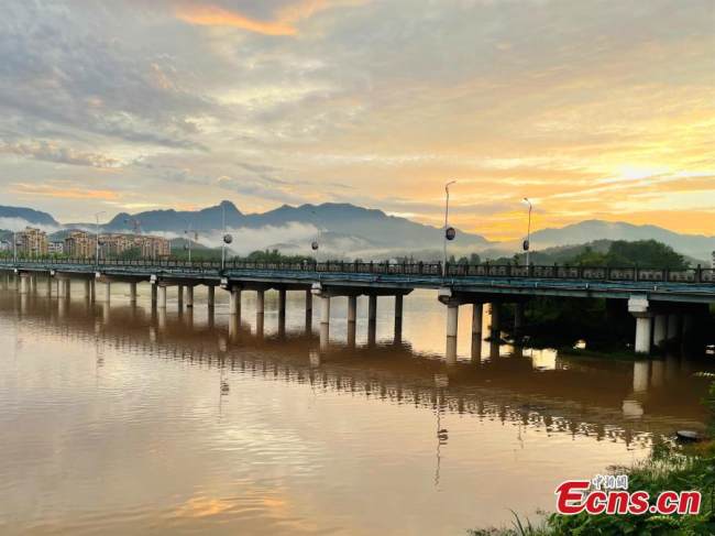 Η γέφυρα, ο ποταμός που ρέει, τα σπίτια και το ηλιοβασίλεμα, δημιουργούν ένα ποιητικό τοπίο μετά από μια δυνατή βροχή στην κομητεία Γιουάν’αν στην επαρχία Χουμπέι, στις 7 Ιουλίου 2021. (Φωτογραφία / Liu Zhongyi)